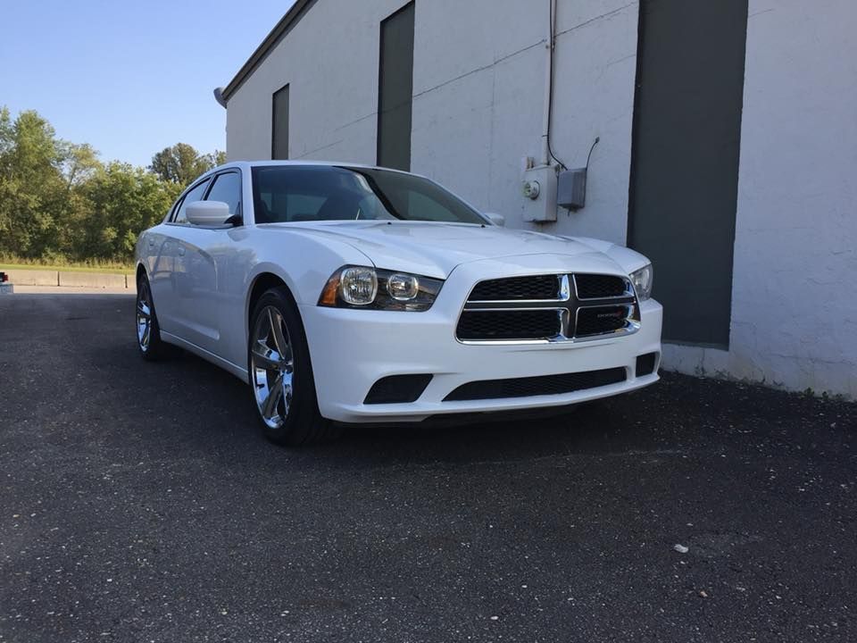 White Dodge Charger parked in front of a white building on an asphalt surface.