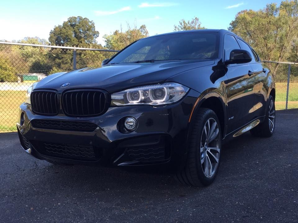 Black BMW SUV parked outdoors, shiny finish, front view, sunlit day.