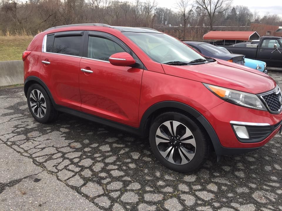 Red Kia Sportage SUV parked on cracked pavement.