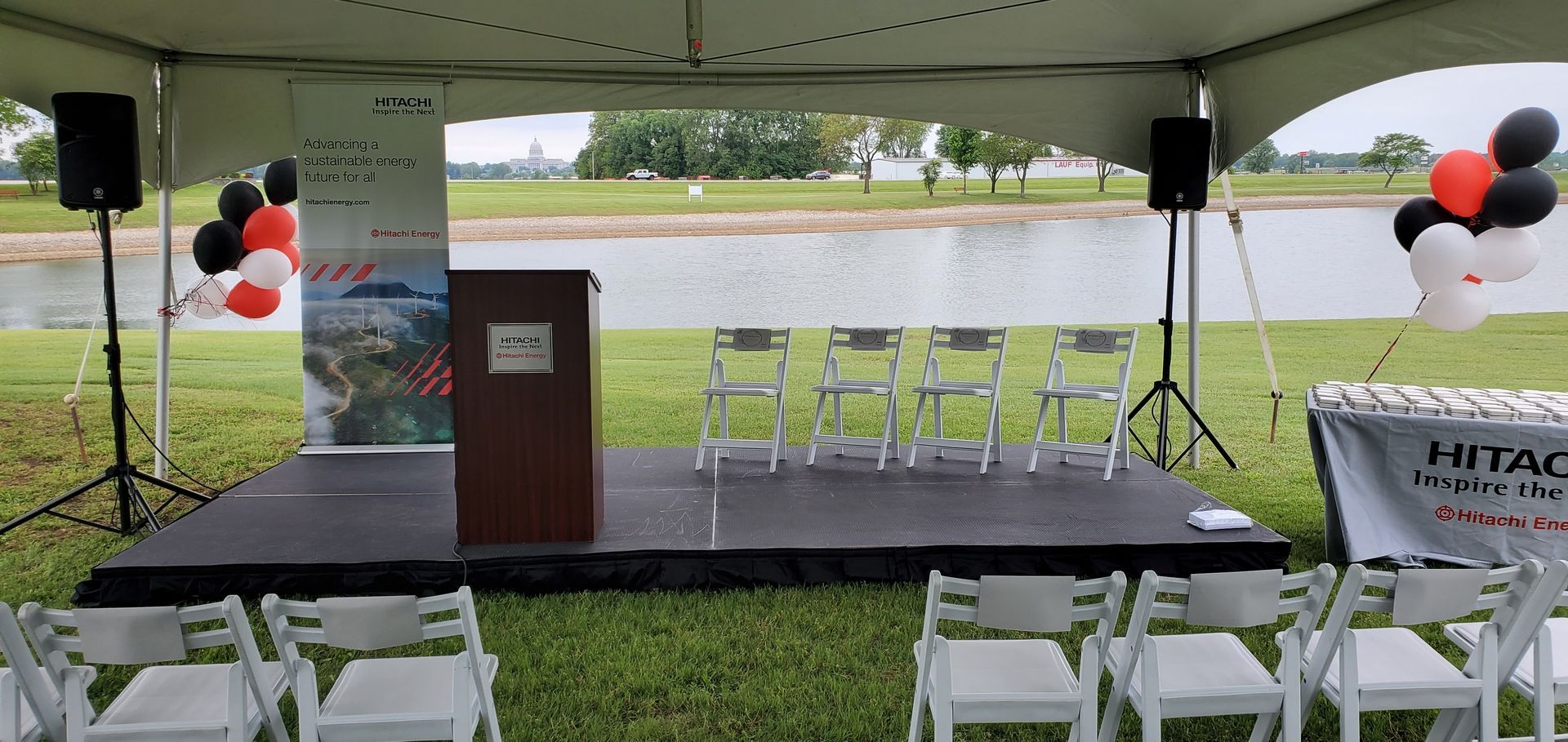 A stage with a podium and chairs under a tent.