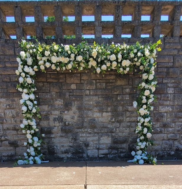 A brick wall is decorated with white flowers and greenery