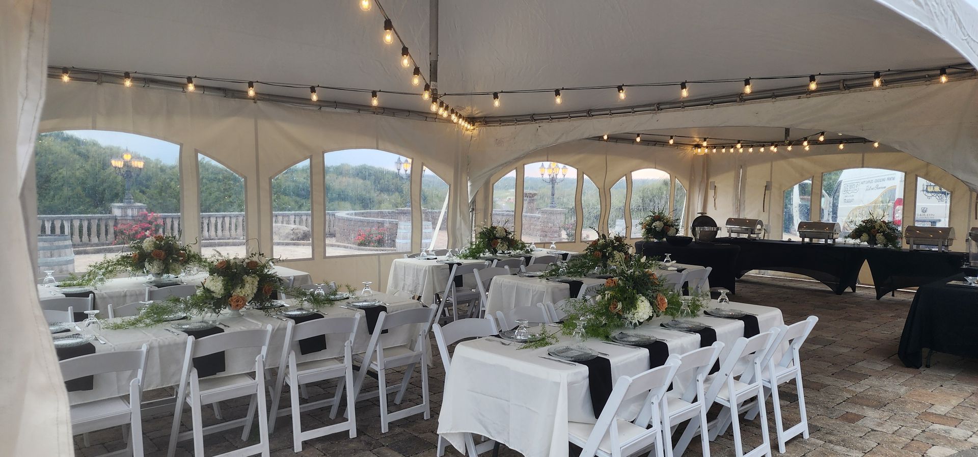 A large tent with tables and chairs set up for a wedding reception.