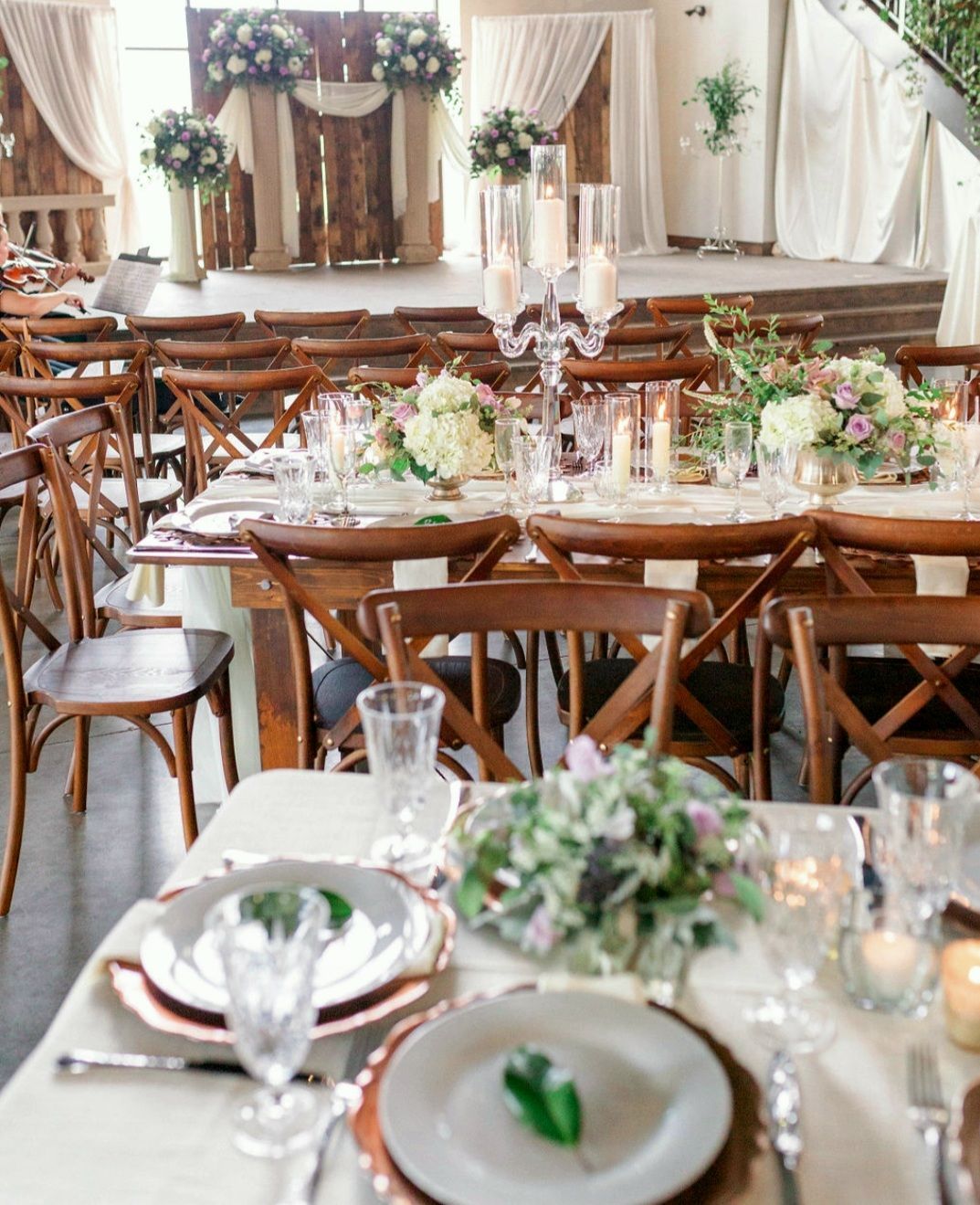 A table set for a wedding reception with plates , glasses , and candles.