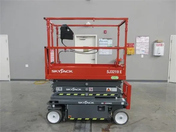 A red skyjack scissor lift is parked in a warehouse