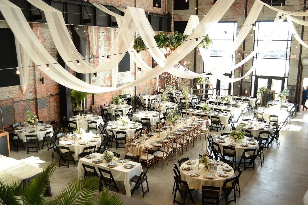 A large room with tables and chairs set up for a wedding reception.