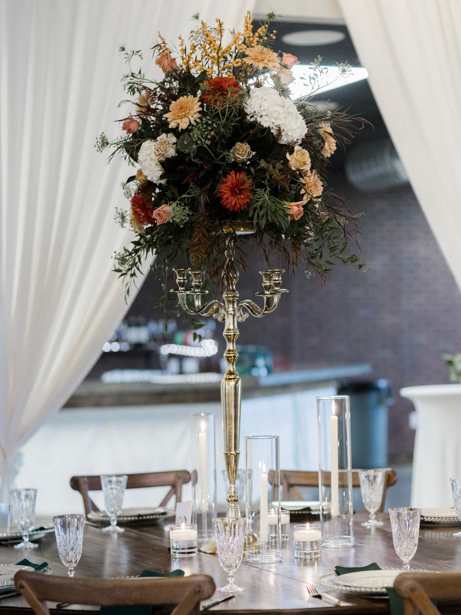 A table with a vase of flowers and candles on it.