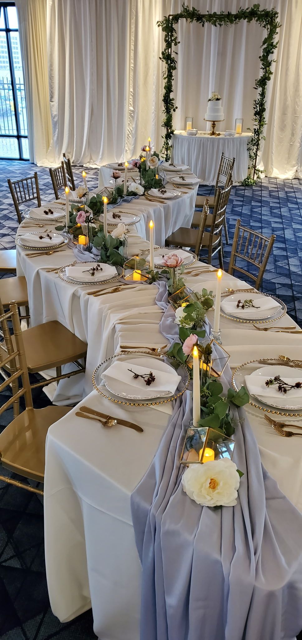 A long table set for a wedding reception with plates , candles , and flowers.