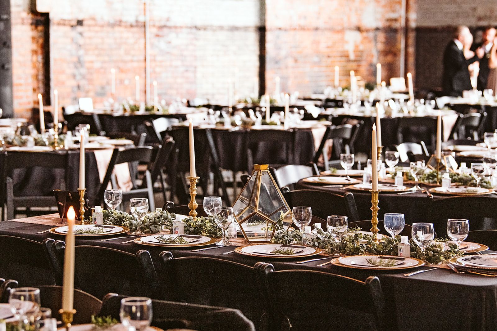 A large room filled with tables and chairs set up for a wedding reception.