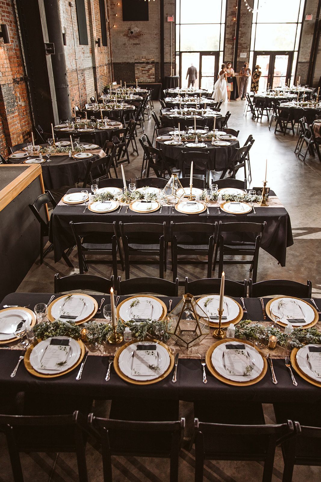 A large room filled with tables and chairs set up for a wedding reception.