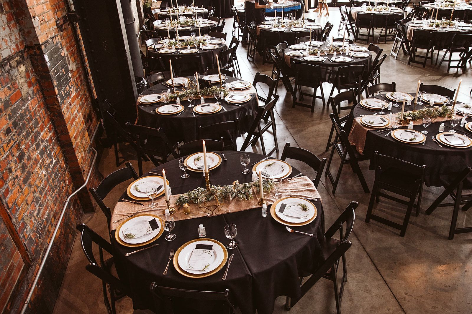 A large room filled with tables and chairs set up for a wedding reception.