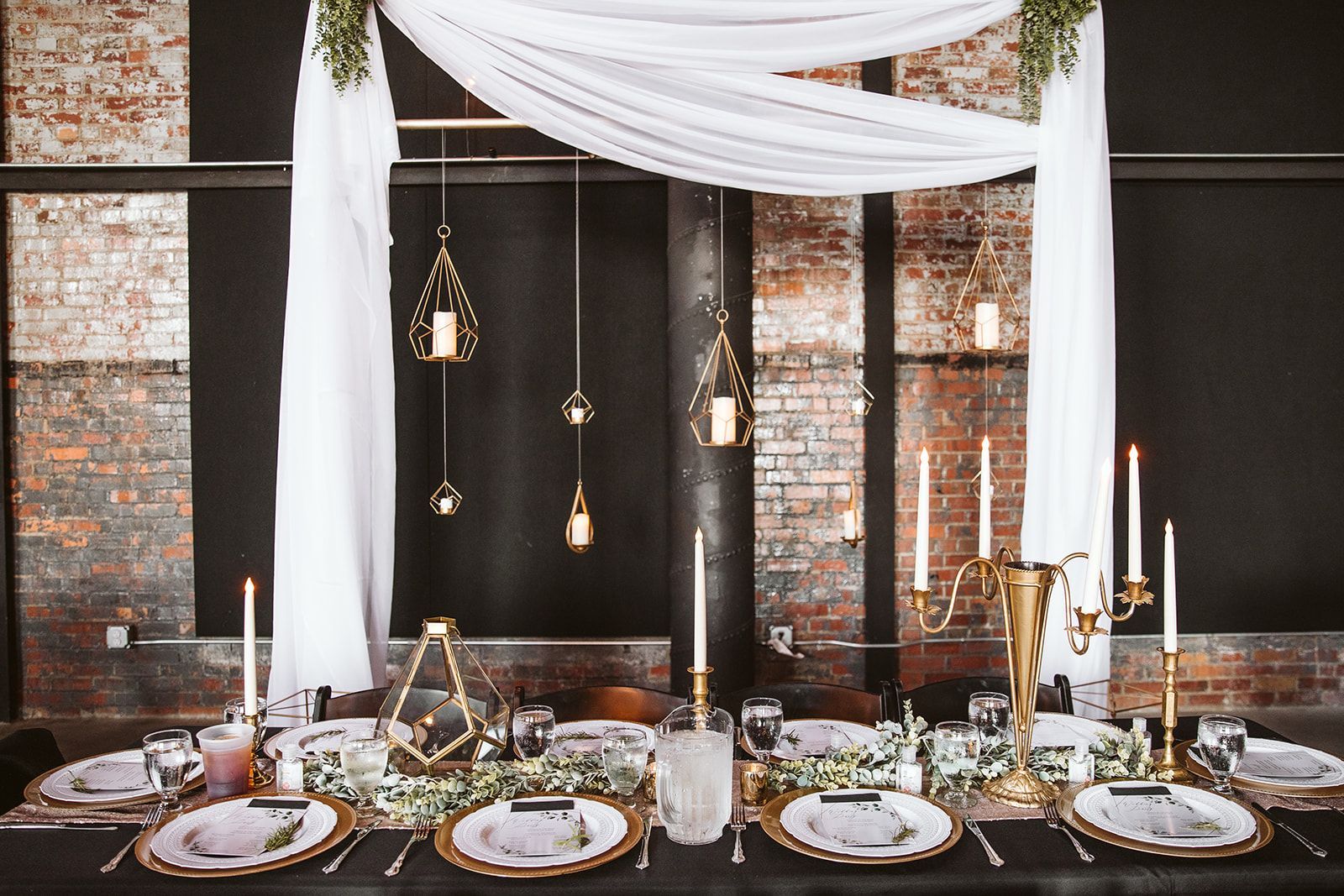 A table set for a wedding reception with plates , candles and a canopy.