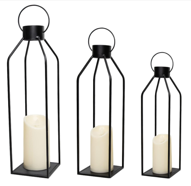 Three black lanterns with white candles inside of them
