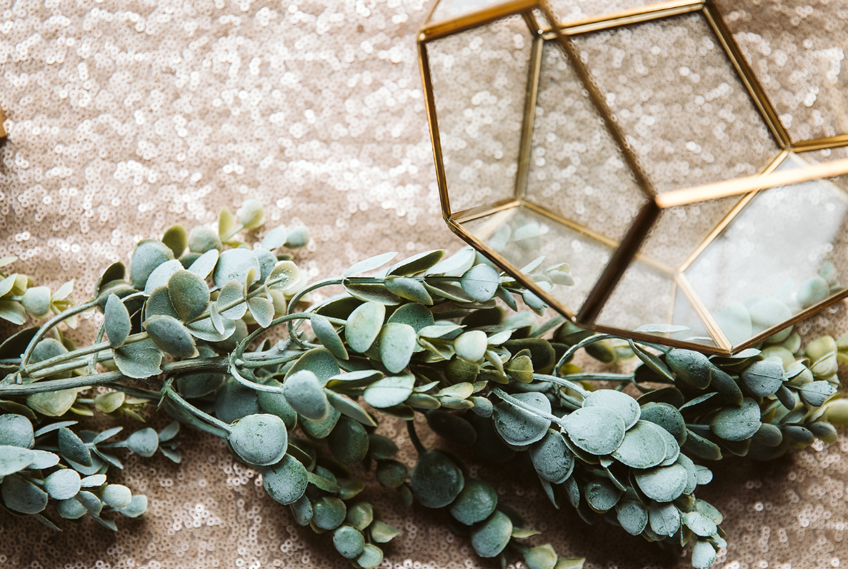 A glass terrarium sitting on top of a table next to a bunch of flowers.