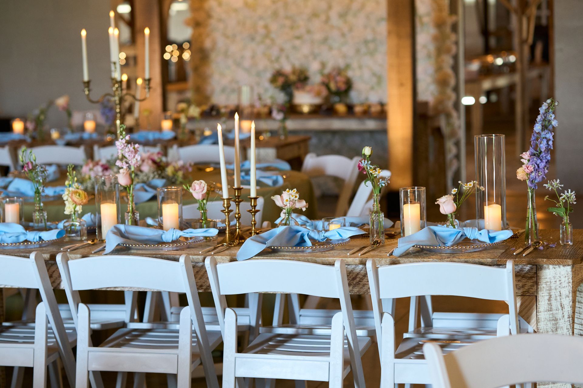 A table set for a wedding reception with candles and flowers on it.