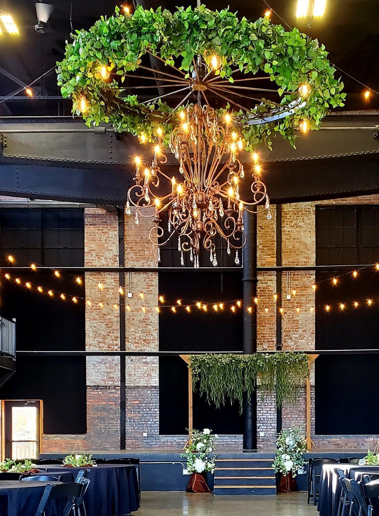 A large chandelier is hanging from the ceiling of a room with tables and chairs.