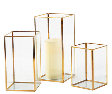 A set of three glass vases with a candle inside of them.
