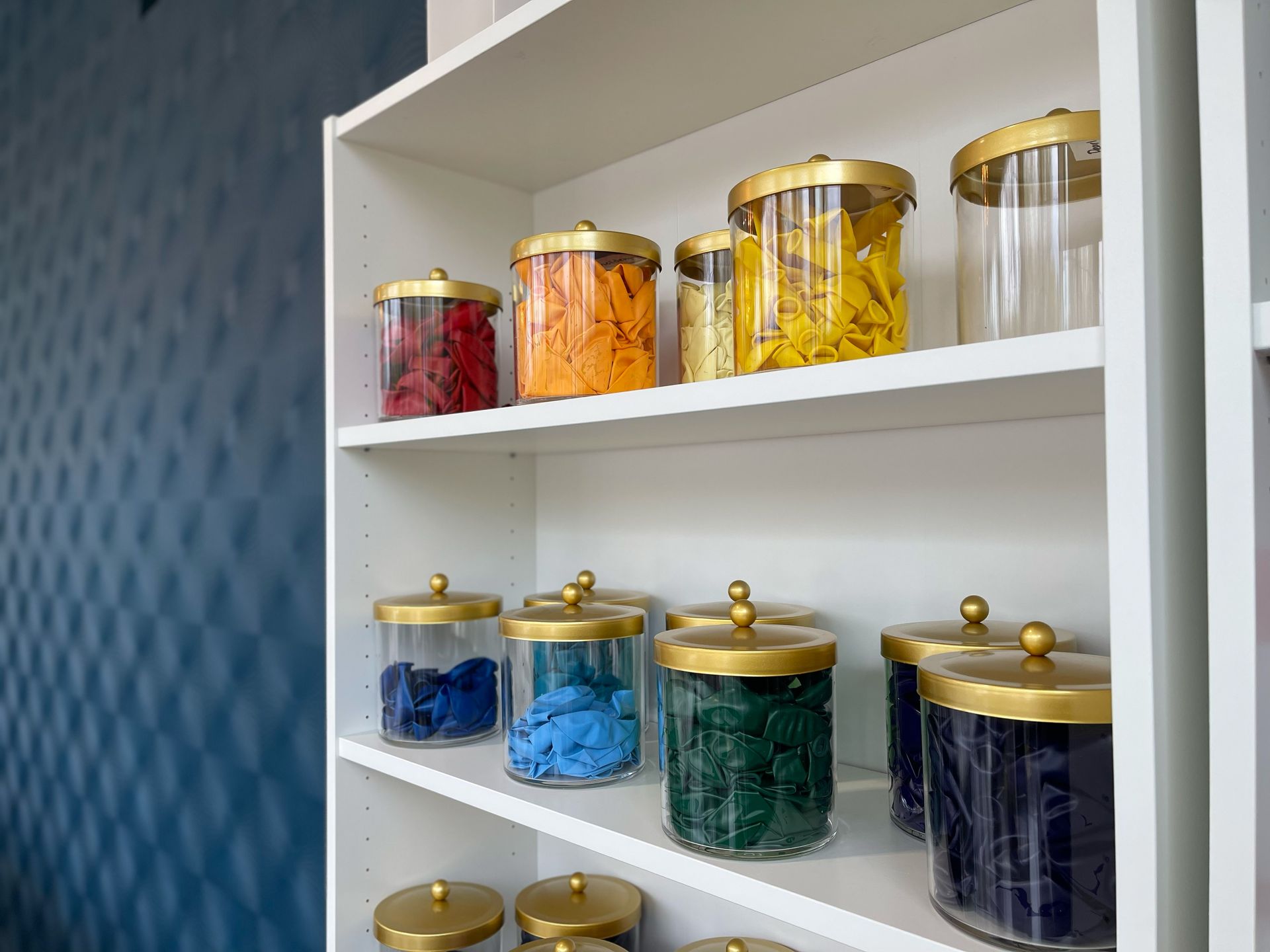 A shelf filled with jars of different colored yarn.