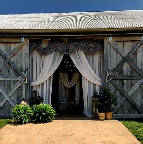 A large wooden barn with white curtains on the doors