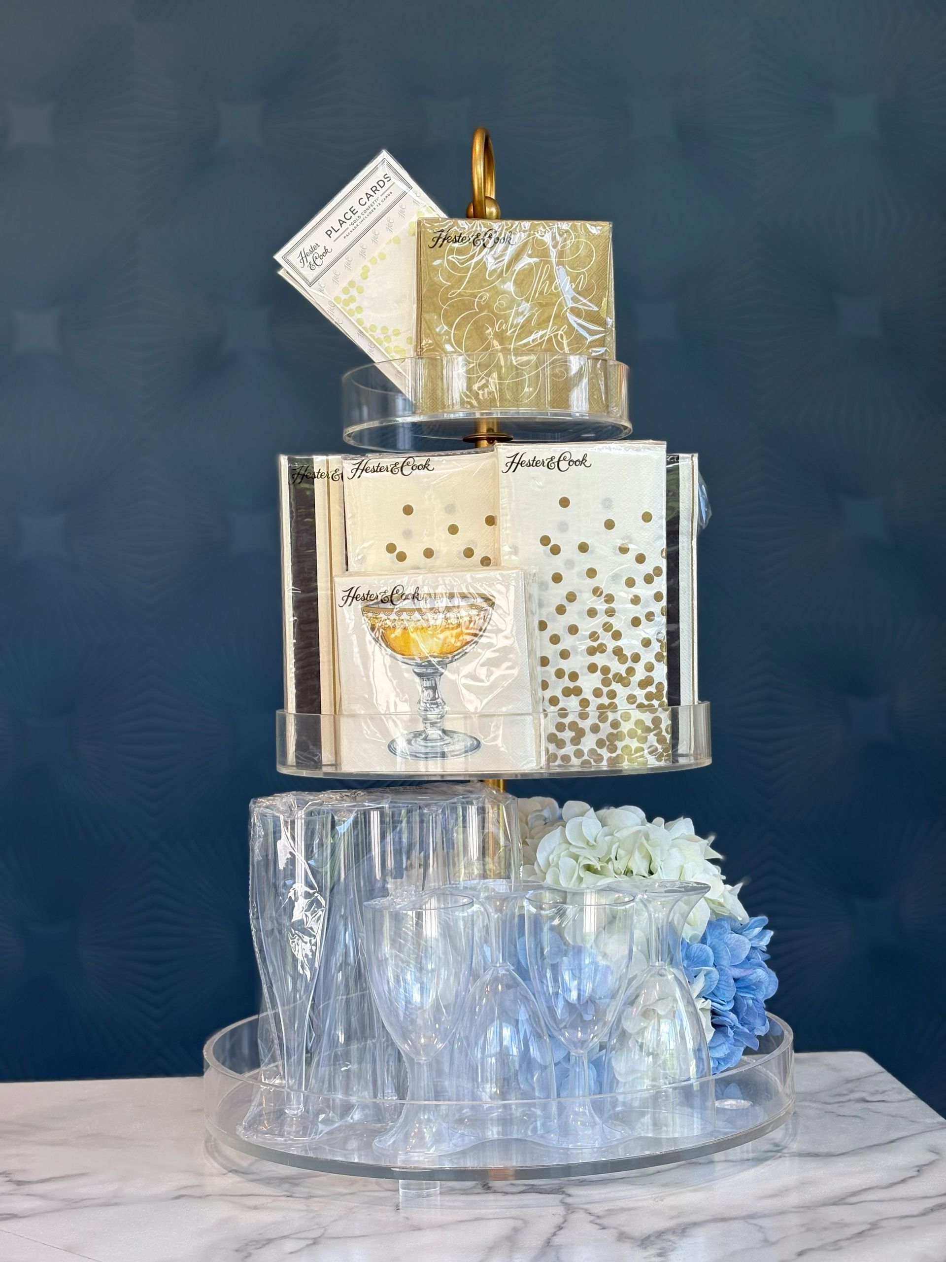 A stack of napkins , glasses , and flowers on a table.
