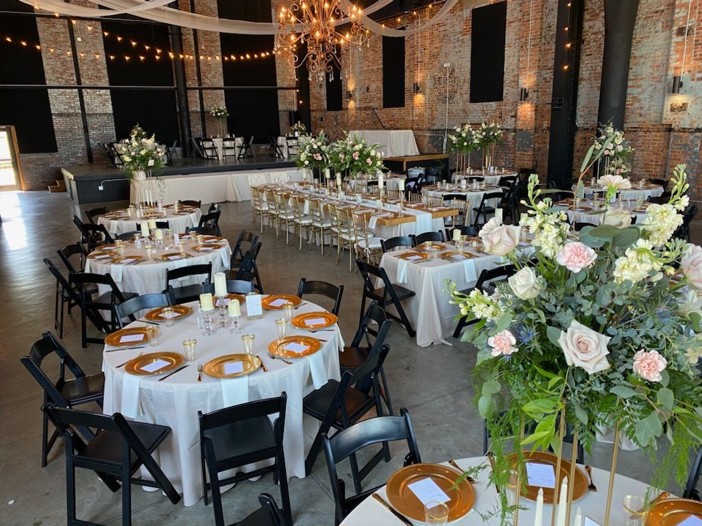 A large room with tables and chairs set up for a wedding reception.