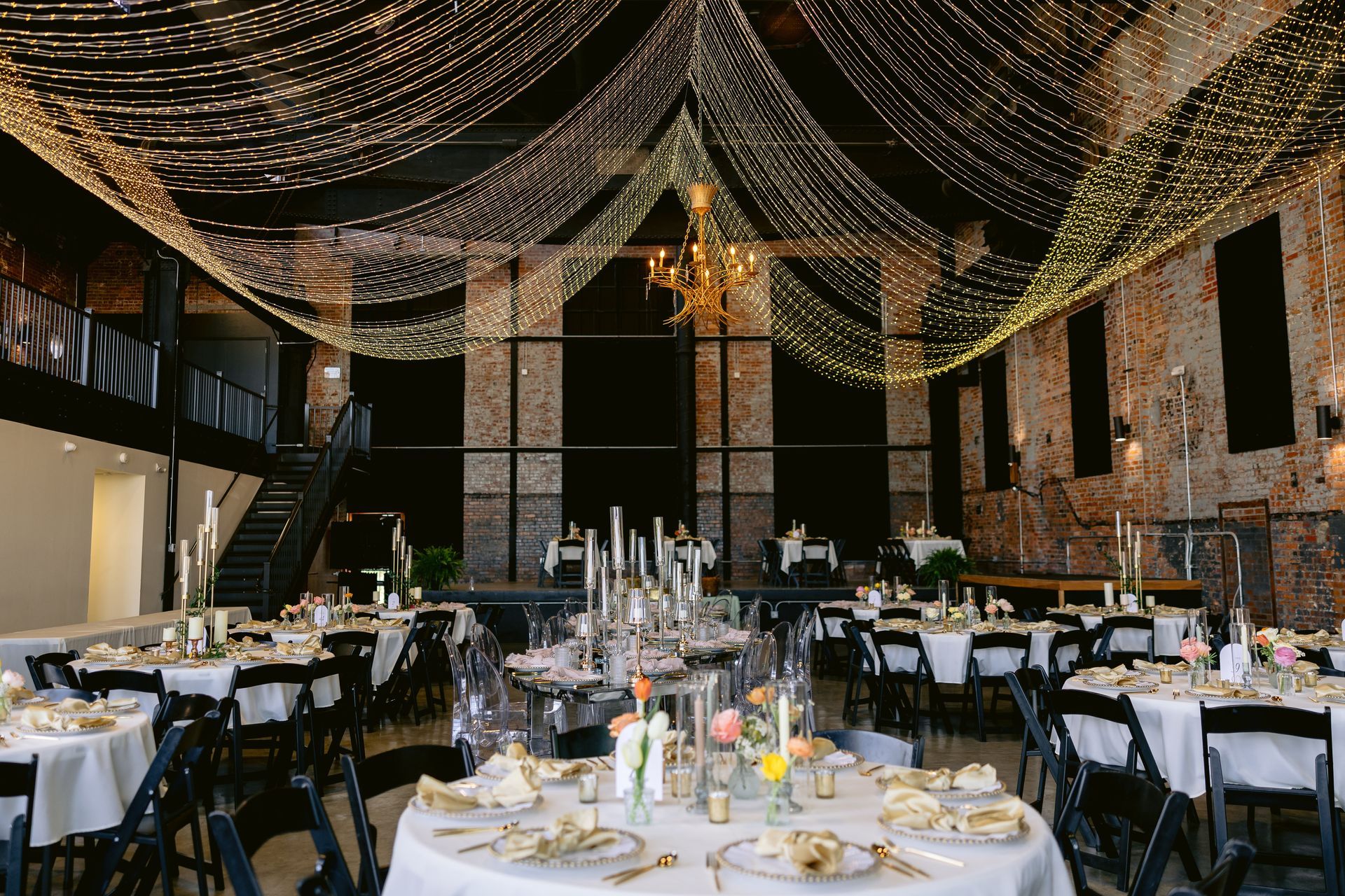A large room with tables and chairs set up for a wedding reception.