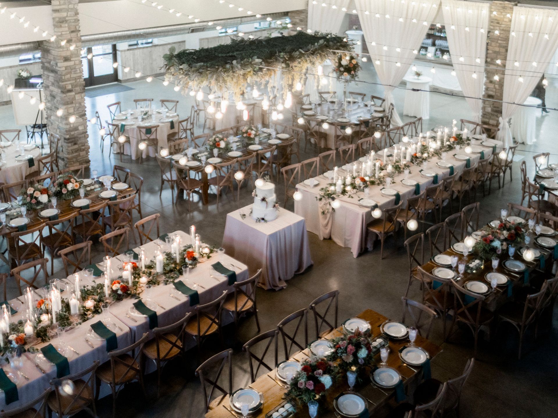 A large room filled with tables and chairs set up for a wedding reception.