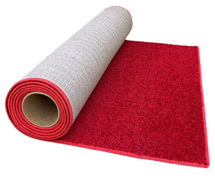 A red rug is rolled up on a white surface