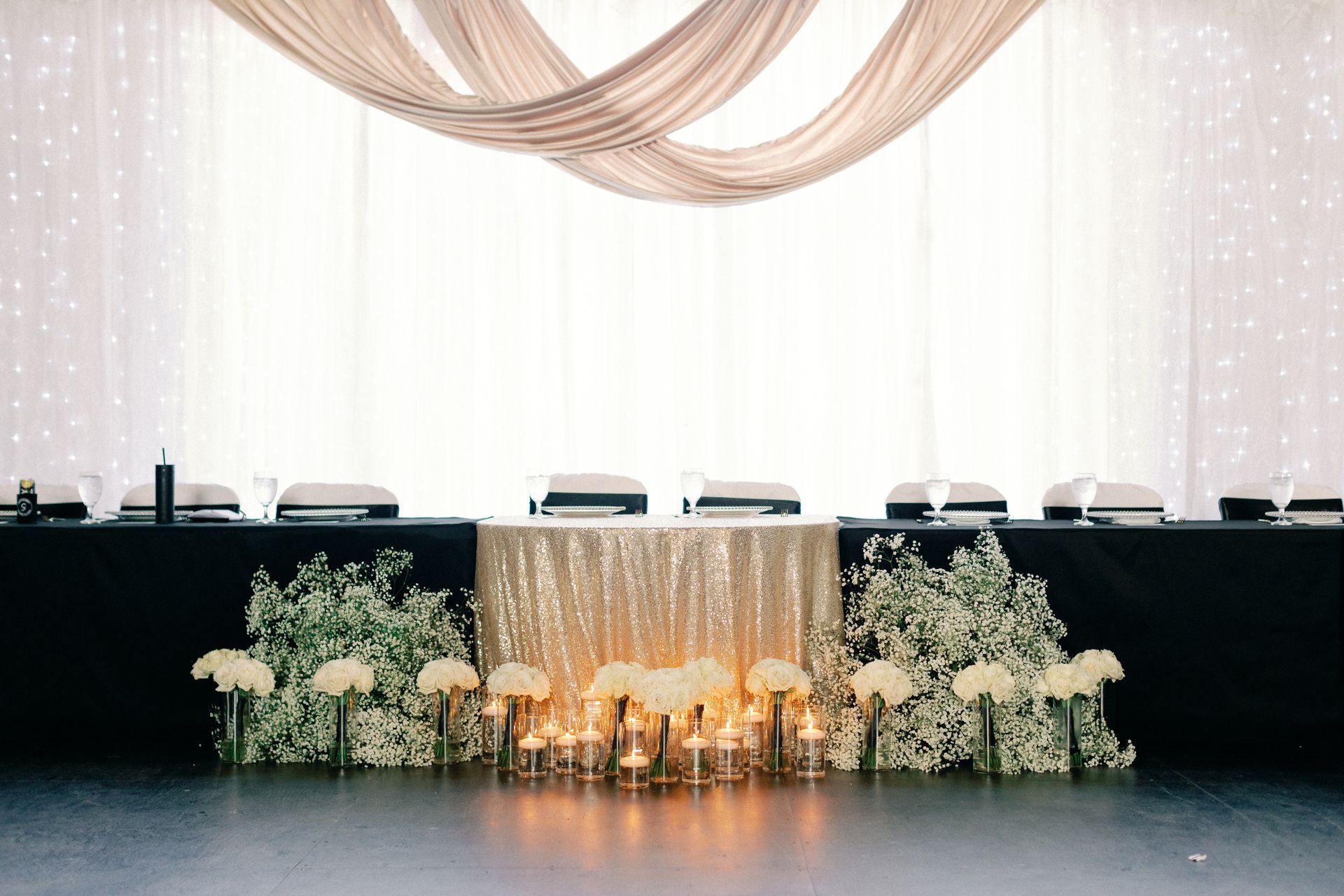 A long table with a gold table cloth and candles on it.