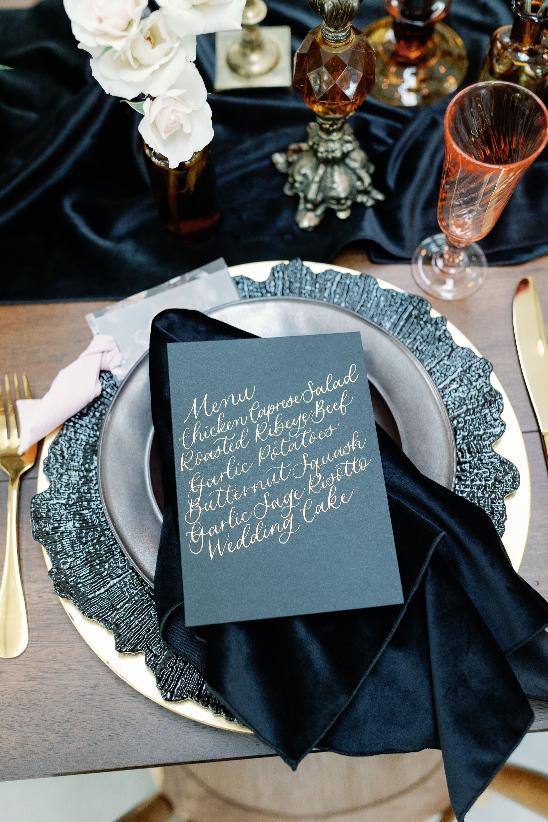 A place setting with a black napkin and a gold plate