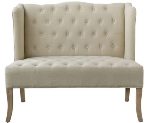 A beige tufted bench with wooden legs on a white background