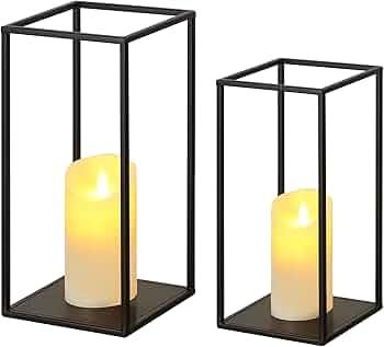 A pair of black metal lanterns with candles inside of them.