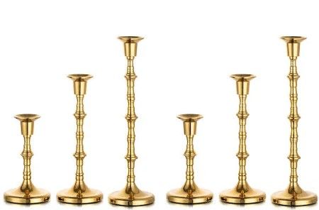 A row of brass candle holders of different sizes on a white background.