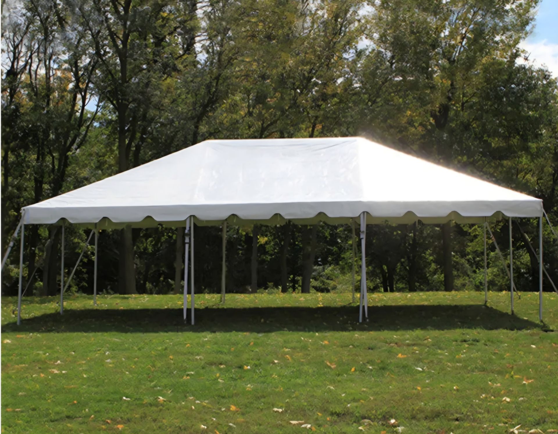 A large white tent is sitting in the middle of a grassy field