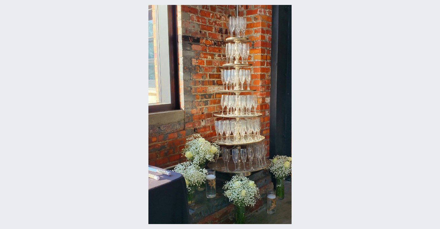 A stack of wine glasses sitting on top of a table in front of a brick wall.