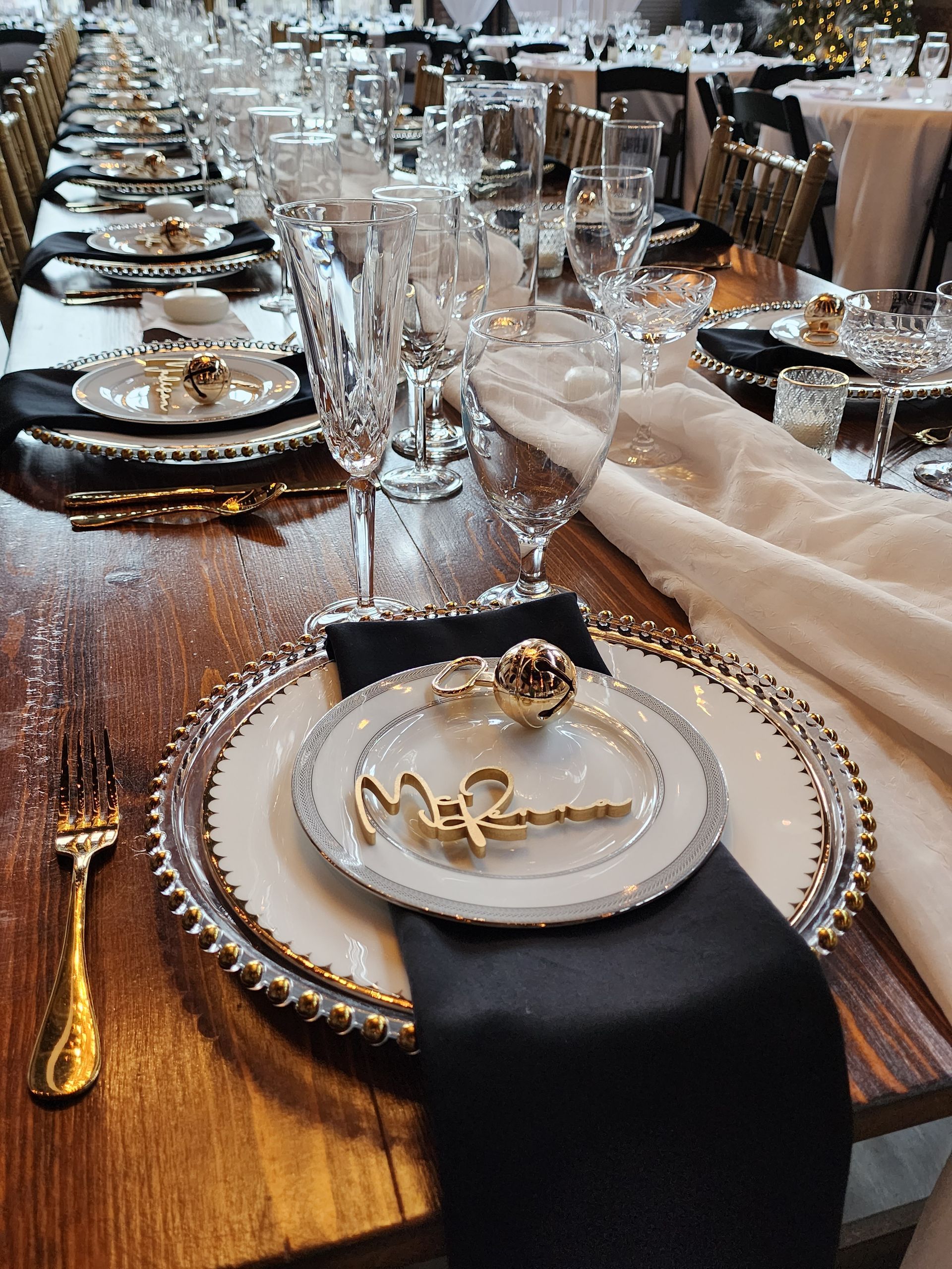 A long wooden table with plates , glasses , and silverware on it.