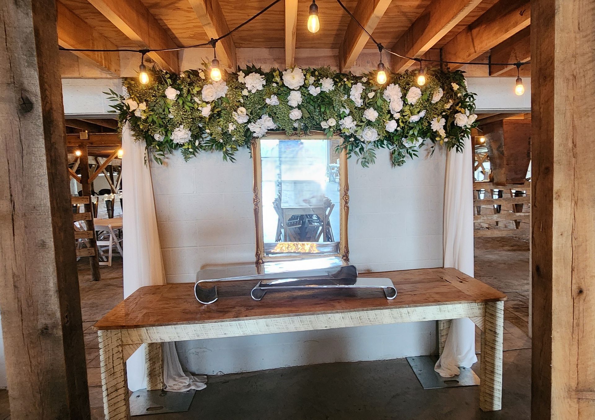 A wooden table with a mirror and flowers on it in a room.
