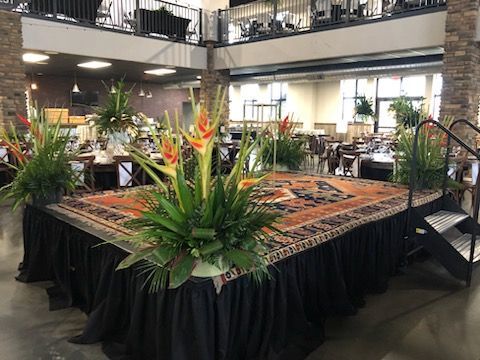 There is a stage with flowers on it in the middle of a room.