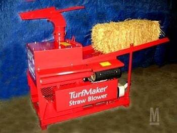 A red machine with a bale of hay on top of it.