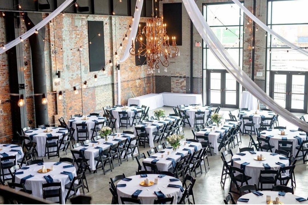 A large room with tables and chairs set up for a wedding reception.
