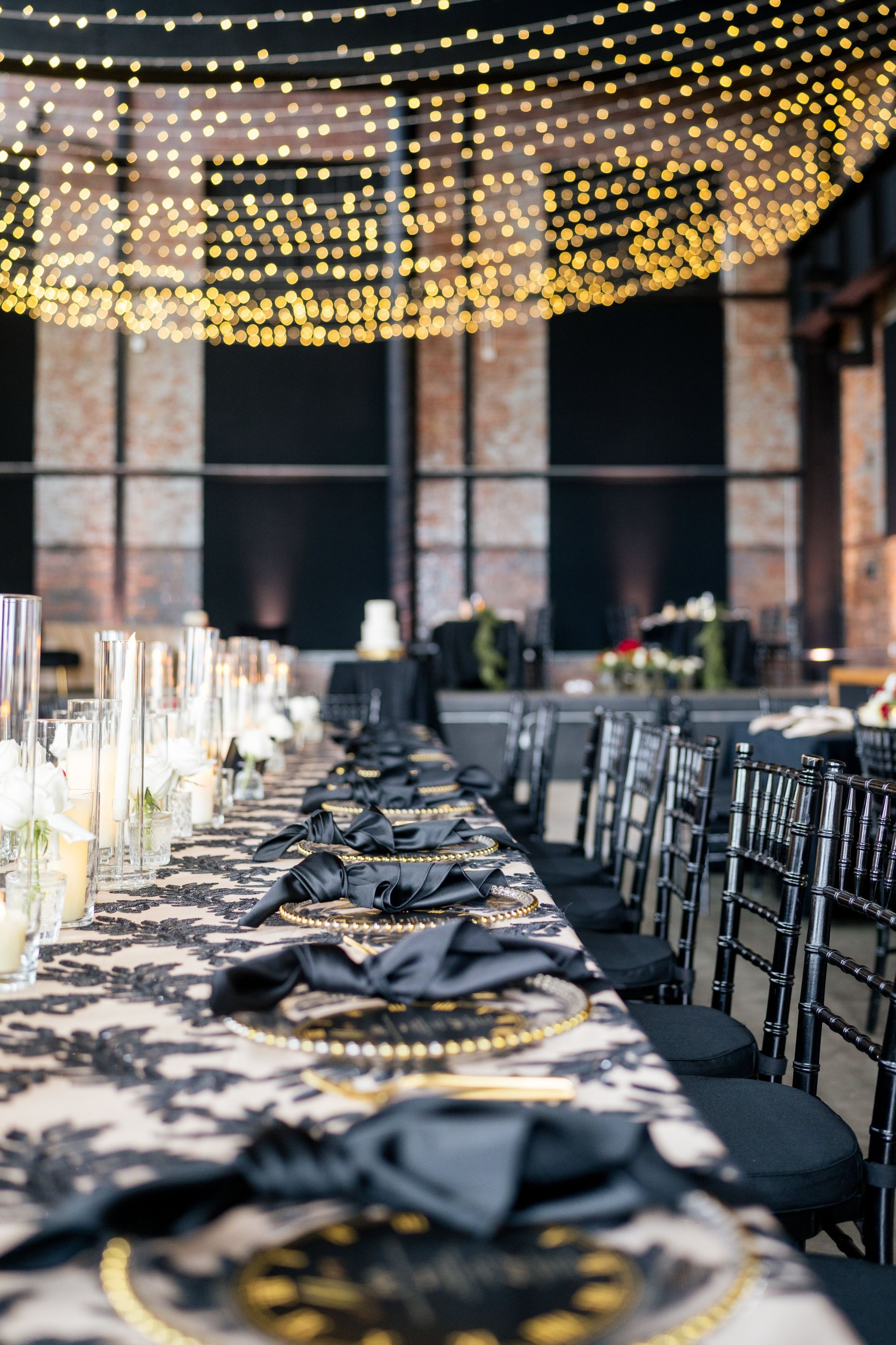 A long table with black and gold plates and napkins set for a wedding reception.