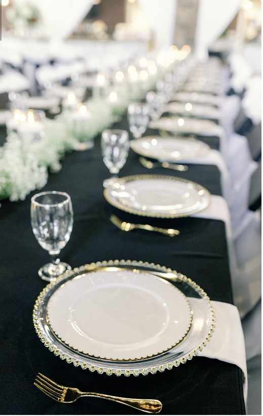 A place setting with a black napkin and a gold plate