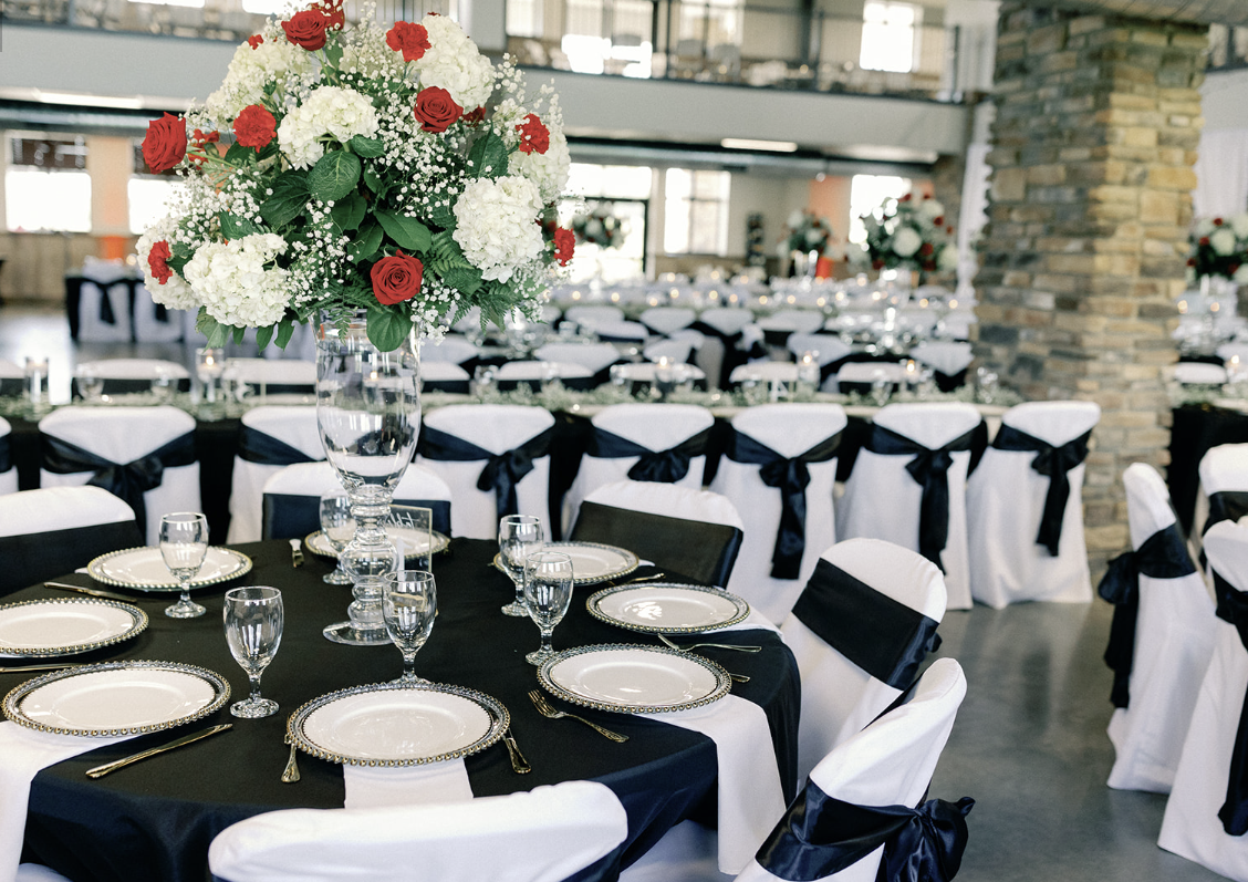 A table set for a wedding reception with a vase of flowers on it