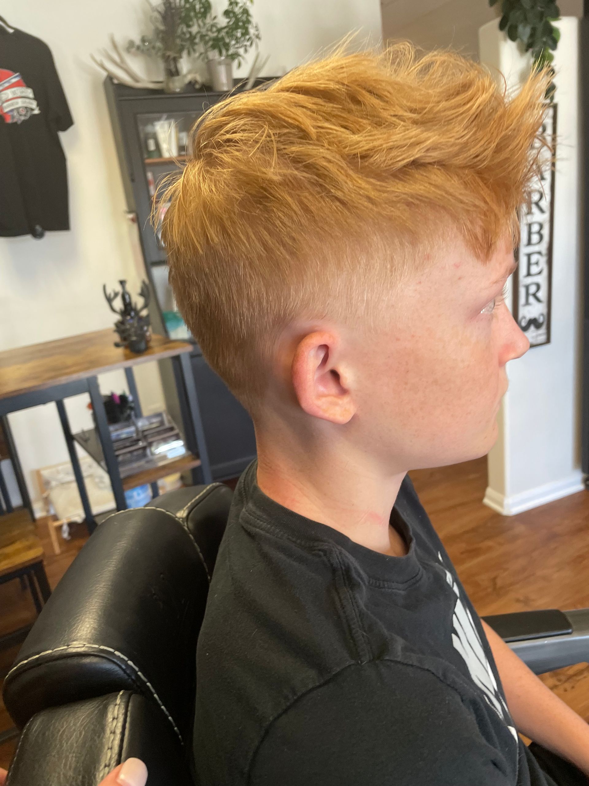 A young person with a reddish-blonde, textured hairstyle and a skin fade haircut.
