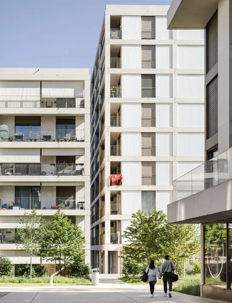 Immeubles d'appartements modernes avec des gens qui se promènent dans une cour par une journée ensoleillée.