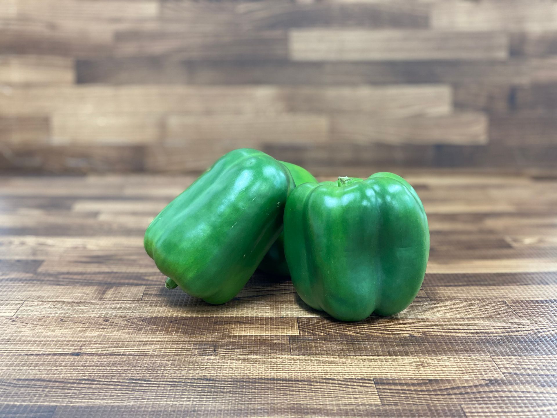 Green bell peppers on a wooden surface.