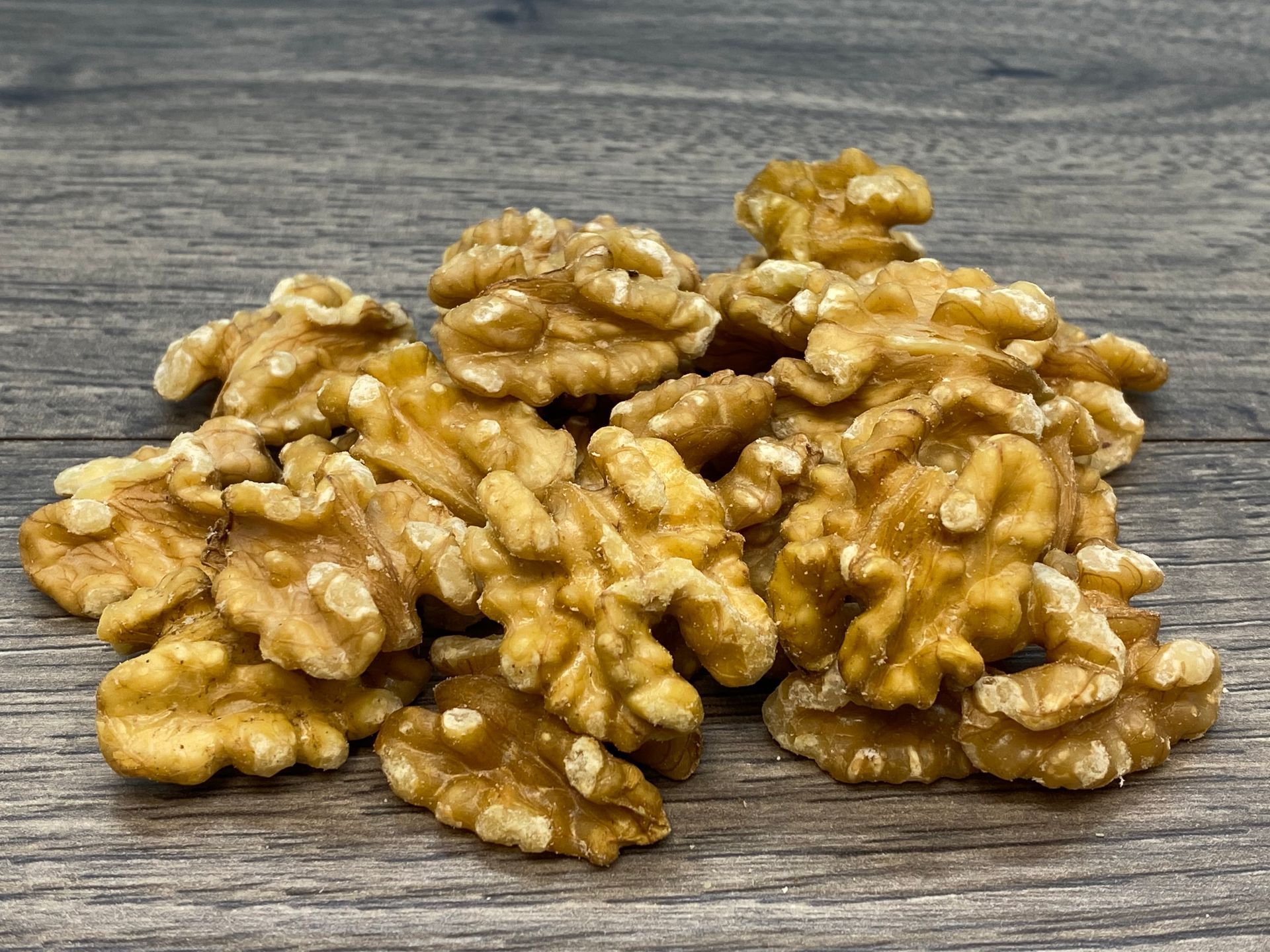 Pile of shelled walnuts on a gray wooden surface.