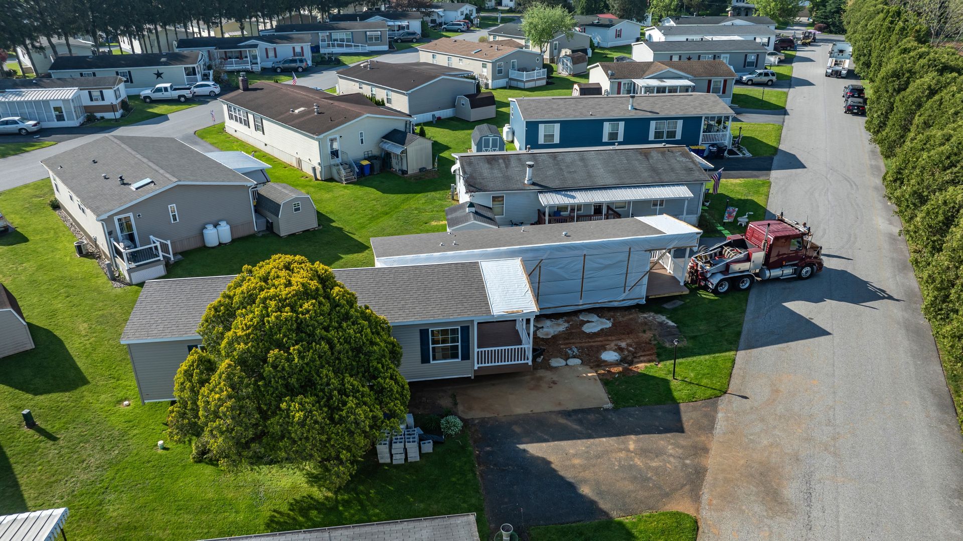 Aerial view of a suburban mobile home park with rows of manufactured homes and parked vehicles.