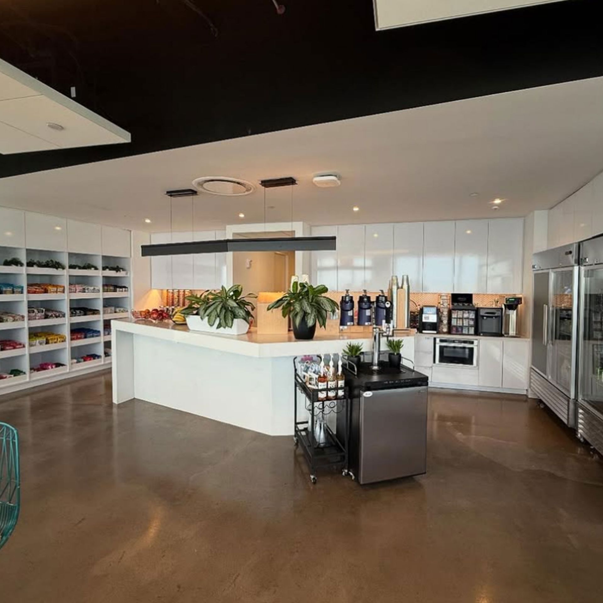Modern café with a central coffee counter, beverage machines, and seating in an open, industrial-style space