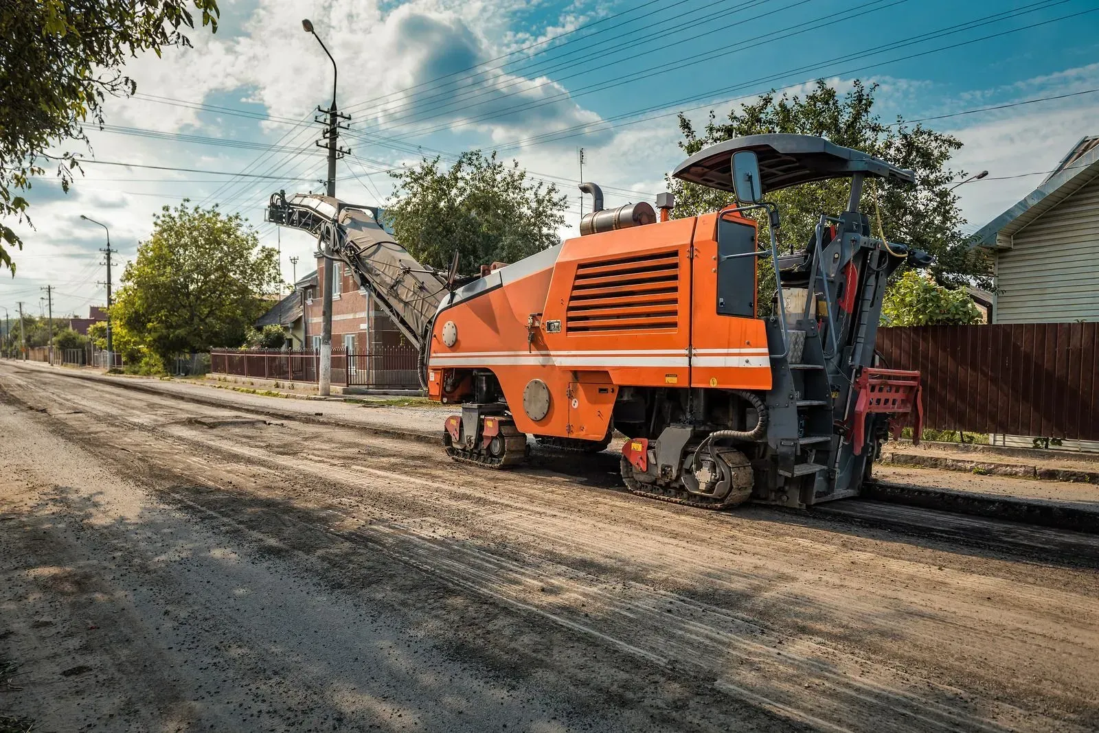 A machine is laying asphalt on the side of a road.