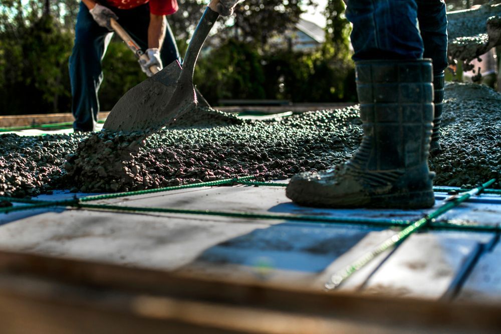 Workers Pouring Wet Concrete With a Shovel Over Green Rebar — Nambucca Concrete Pumping in Grafton, NSW